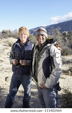 Portrait of two young male friends standing together with binoculars