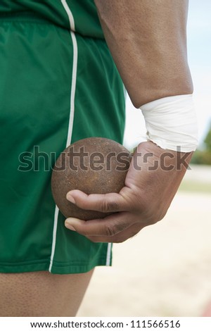 Male athlete holding metal ball on track and field