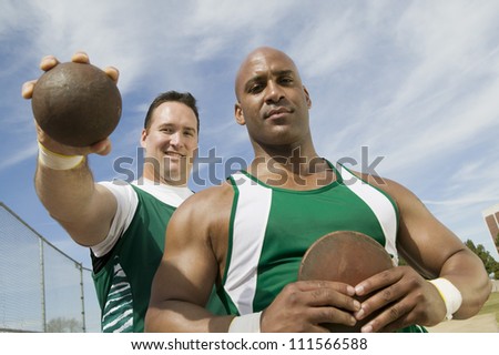 Male athletes holding shot put and discus