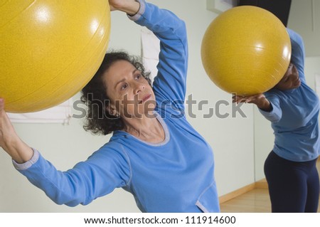 Senior woman using exercise balls in fitness class
