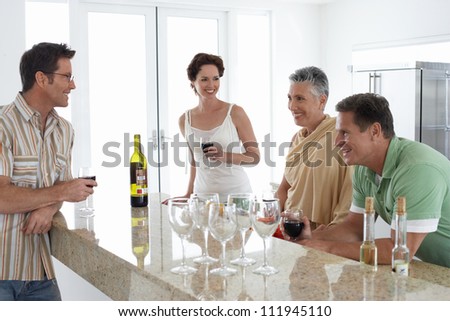 Happy middle aged couple having wine with their children in kitchen