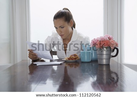Woman going through document while having breakfast