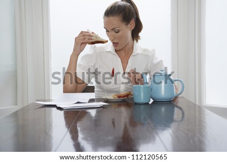 Beautiful woman looking at stain on shirt while having breakfast