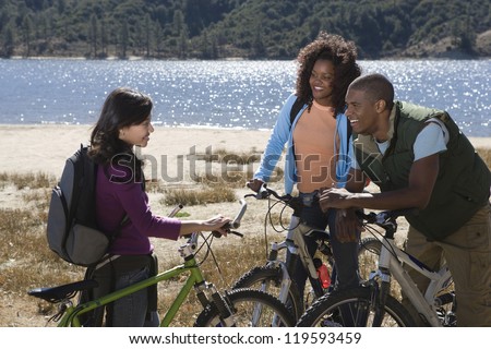 Happy multiethnic friends with bicycle having discussion