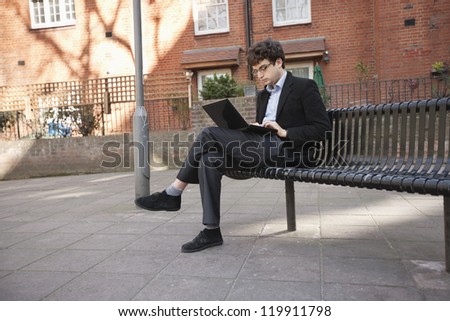 Young businessman using laptop while sitting on bench