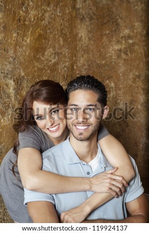 Portrait of happy young woman hugging man from behind