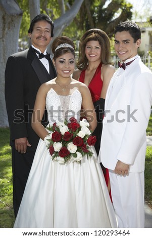 Portrait of a happy newlywed couple standing with friends at lawn