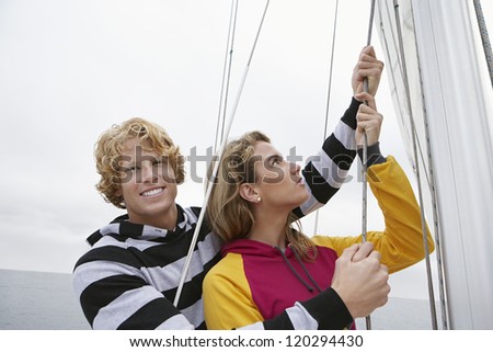 Happy Caucasian couple holding rope on sail boat