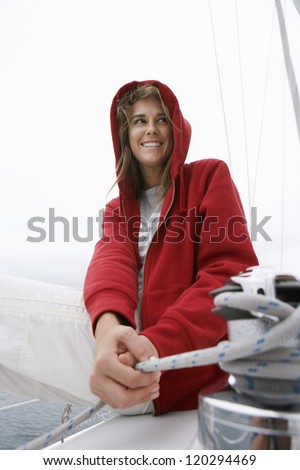 Happy young woman in red hooded jacket sailing on boat