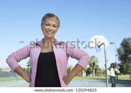 Portrait of a beautiful woman with hands on waist and friend in the background