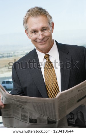 Portrait of a happy middle aged business man reading newspaper