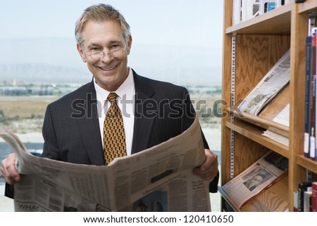 Portrait of a middle aged business man reading newspaper in library