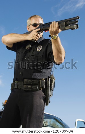 Low angle view of a police officer aiming with gun