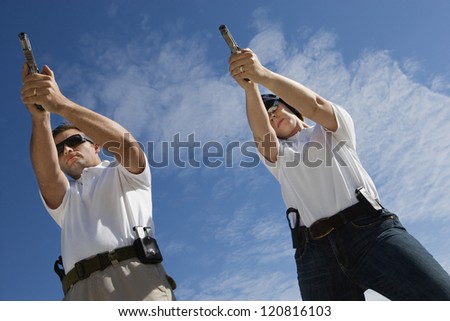Two persons aiming target with handgun, low angle view