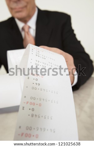 Senior male accountant with calculator paper tape