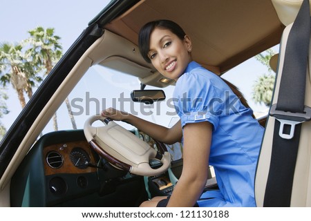 Low angle view of young Indian business woman in car holding steering wheel