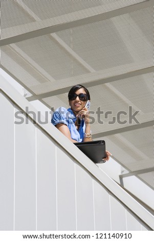 Low angle view of a happy Indian business woman on call in office balcony