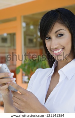 Portrait of a beautiful Indian business woman text messaging on cell phone