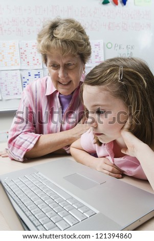 Teacher teaching preadolescent student from laptop in the classroom