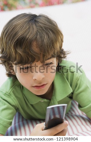 Preadolescent boy using cell phone while lying on bed