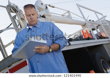 Low angle view of a mechanic writing notes on clipboard against a truck