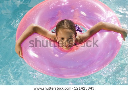 Portrait of a happy preadolescent girl with inflatable tube in swimming pool