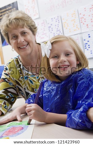 Portrait of female student painting with teacher in art class