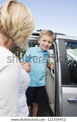 Mature woman helping grandson get down from minivan