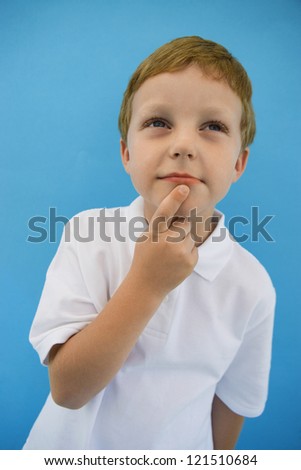 Cute little boy in a white t-shirt pondering with finger on chin over colored background