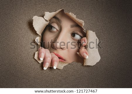 Young Middle eastern woman looking away from ripped paper hole