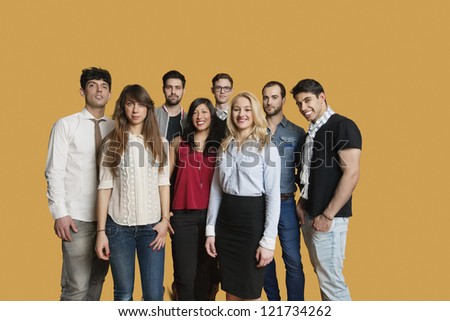 Portrait of happy multi ethnic group of friends standing together over colored background