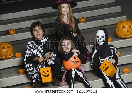 Portrait of happy friends sitting together on stairs in Halloween outfit