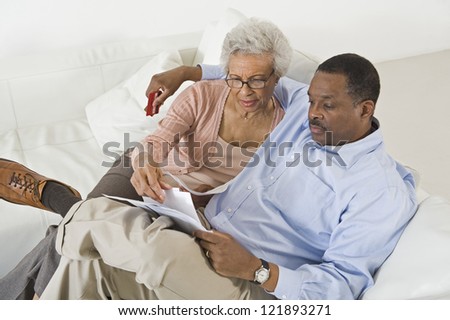High angle view of senior African American couple looking at bills while sitting on sofa