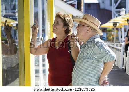 Caucasian senior woman looking at shop window with man