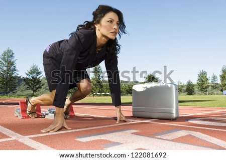 Confident business woman at start position of a racing track with briefcase against sky