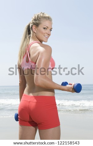 Portrait of healthy young woman in sportswear exercising with hand weights