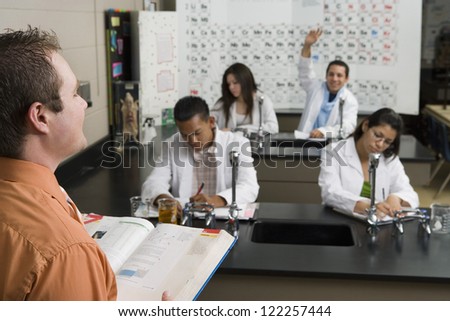 Professor asking question while student raising hand in classroom