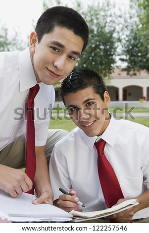 Male students in uniform studying together outdoors