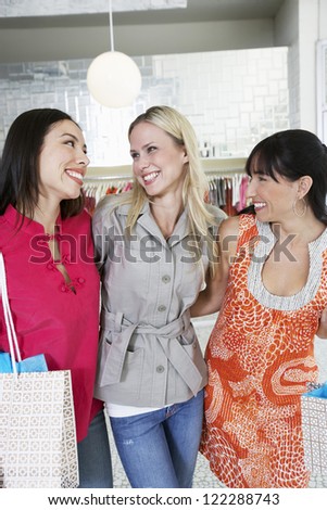 Portrait of female friends standing together in clothing store