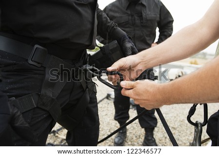 Man's hand fixing harness on commando's waist