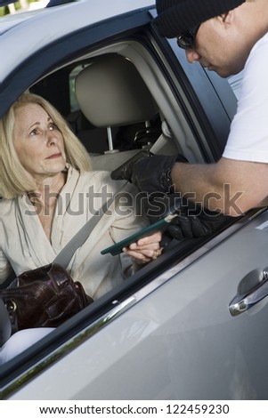 Thief with gun taking woman\'s wallet through car window