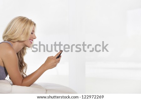 Side view of beautiful young woman reading text message on cell phone (Slight grain)