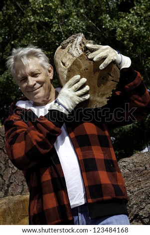 Senior man carrying firewood over his shoulders