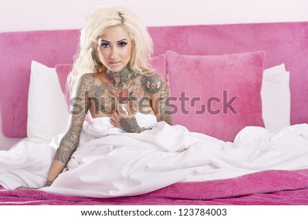 Portrait of a tattooed woman covering herself bed sheet