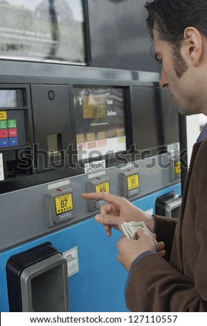 Man using petrol pump machine while holding money