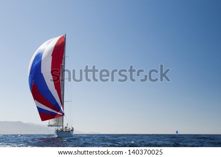 Yacht in the blue ocean with full sail against the clear sky