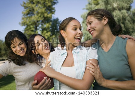 Four happy women in the park one female holding American football