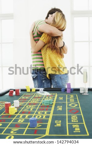 Side view of a young man hugging woman at roulette table