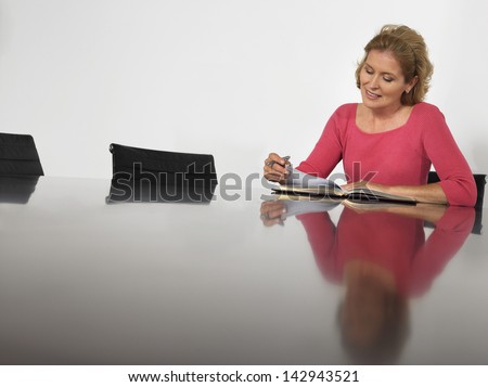 Beautiful businesswoman reading book in conference room