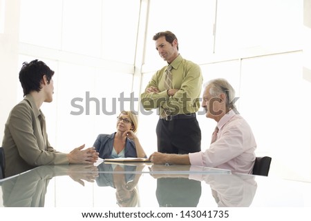 Business people listening to female executive during meeting at conference table